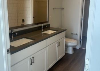 A bathroom with a toilet, sink, and mirror.
